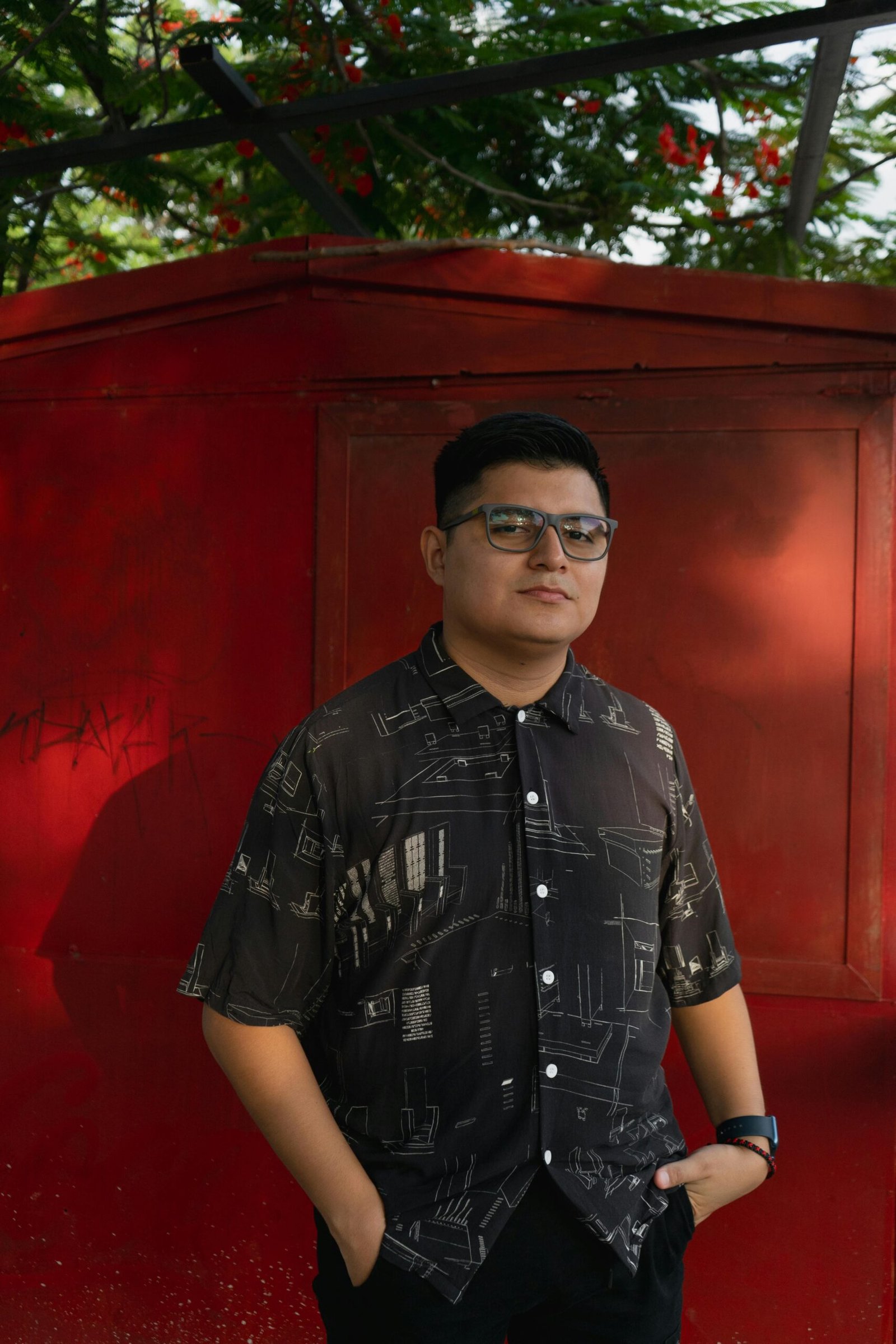 Casual portrait of a man with glasses in front of a red wall in Merida, Yucatan.